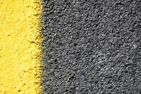 close up of a dark grey asphalt road divided by yellow paint