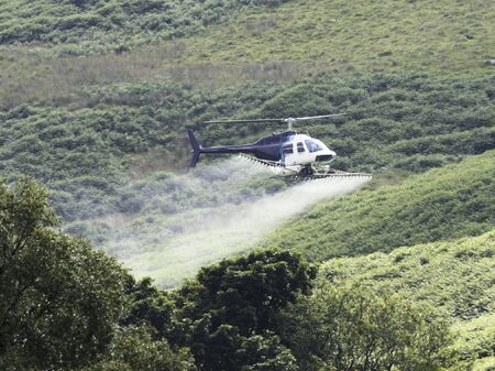 Crop sprayer duster helicopter, spraying mountains, fields and landの写真素材