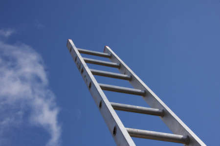 Bright silver ladder against a blue sky の写真素材