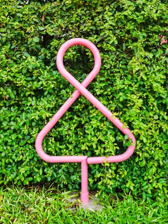 Public toilet graphic sign, Female rest room outdoor symbol made from round steel pipe post with green tree wall backgroundの写真素材