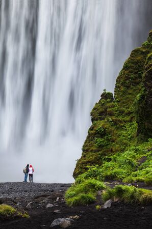 Tourists admire Skogarfoss waterfall in Icelandの写真素材