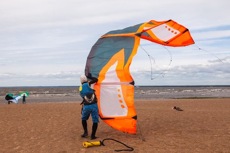 Kite surfer wearing a wetsuit is preparing his kite on a windy cold dayの写真素材