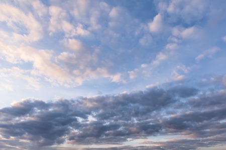 Background with dark, white and pink clouds against the blue skyの写真素材