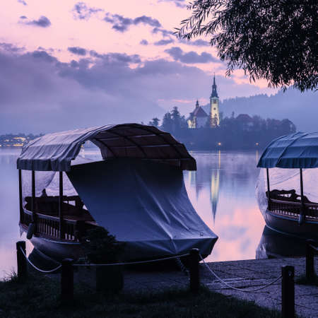 Sunrise over Bled Lake, island with Pilgrimage Church, boat for tourists, Slovenia.の写真素材