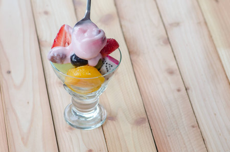 strawberry yogurt topping over mixed fruit and berry on wood table, healthy food, selective focusの写真素材