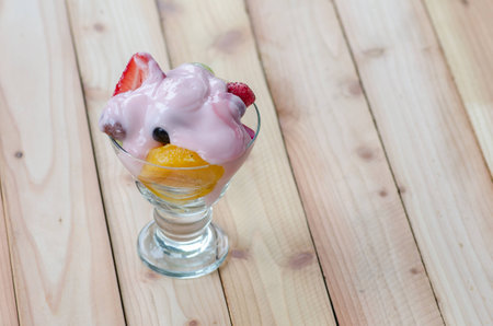 strawberry yogurt topping over mixed fruit and berry on wood table, healthy food, selective focusの写真素材
