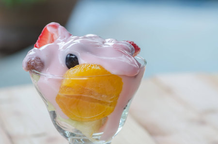 strawberry yogurt topping over mixed fruit and berry on wood table, healthy food, selective focusの写真素材