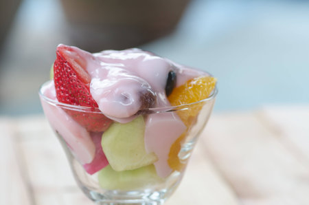 strawberry yogurt topping over mixed fruit and berry on wood table, healthy food, selective focusの写真素材