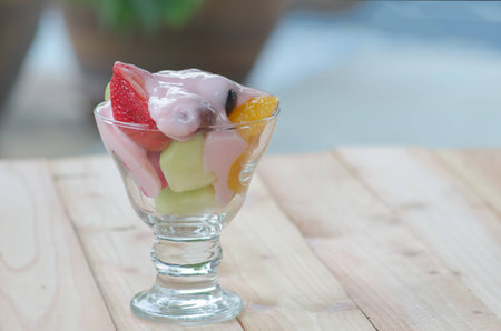 strawberry yogurt topping over mixed fruit and berry on wood table, healthy food, selective focusの写真素材