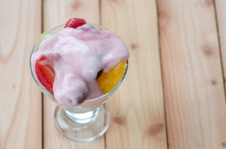strawberry yogurt topping over mixed fruit and berry on wood table, healthy food, selective focusの写真素材