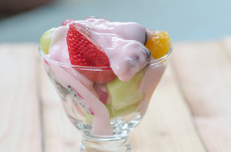 strawberry yogurt topping over mixed fruit and berry on wood table, healthy food, selective focusの写真素材