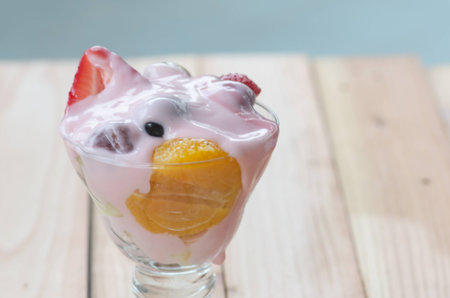 strawberry yogurt topping over mixed fruit and berry on wood table, healthy food, selective focusの写真素材