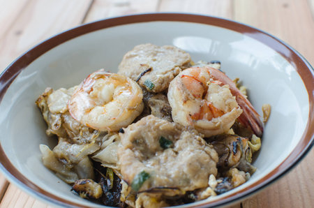 Mixed fried noodle with shrimp and pork on wood tableの写真素材