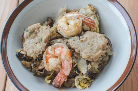 Mixed fried noodle with shrimp and pork on wood tableの写真素材