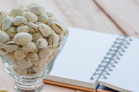 pistachio and notebook on wooden table