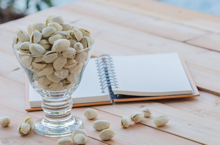 pistachio and notebook on wooden tableの写真素材
