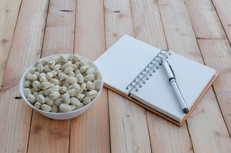 pistachio and notebook on wooden tableの写真素材
