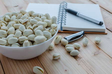 pistachio and notebook on wooden tableの写真素材