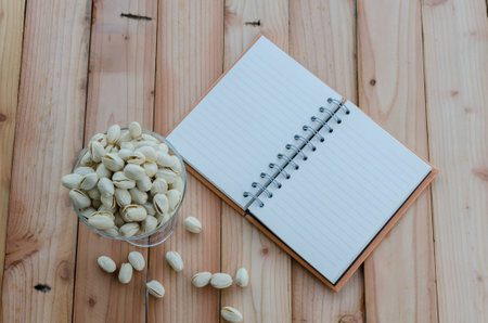 pistachio and notebook on wooden tableの写真素材