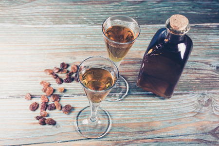 Close-up of glasses of cognac, bottle and raisin