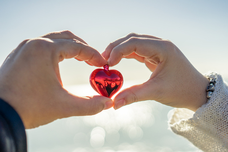 Hands holding Christmas heart against of cloudy skyの写真素材