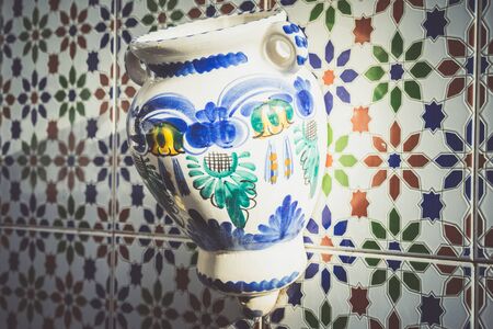 Handmade enamel decorated vase on patterned ornamental wall