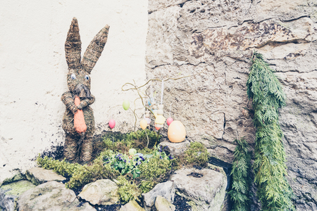 Easter rabbit with painted eggs on moss against of stone wall outdoor