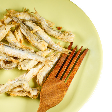 Close-up of pile of fried fish with wooden fork on white kitchen towelの写真素材