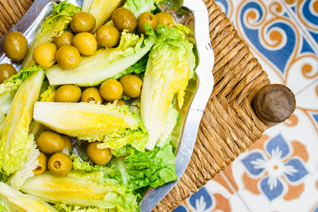 Washed ripe salad with green olives on silver trayの写真素材