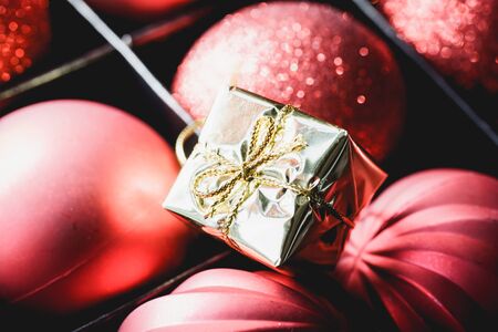 Close up of red festive baubles and tiny gold gift box in packageの写真素材