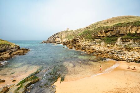 SANTA JUSTA BEACH,CANTABRIA,SPAIN - 31 AUGUST,2016: View of idyllic bay at rocky land with tourists swimming in waterのeditorial素材