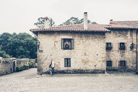 SANTILLANA DEL MAR,CANTABRIA,SPAIN - 31 AUGUST,2016: Old stone building with several windows decorated with plants in potsのeditorial素材