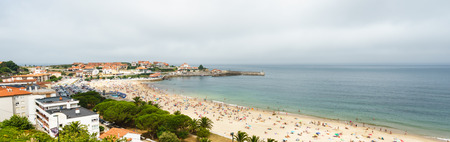 COMILLAS,CANTABRIA,SPAIN - 31 AUGUST,2016: Panoramic view over the beach full of tourists under overcast skyのeditorial素材