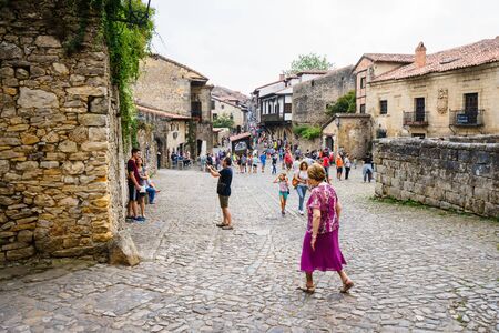 SANTILLANA DEL MAR,CANTABRIA,SPAIN - 31 AUGUST,2016:Tourists walking along paved street with ancient buildings.のeditorial素材