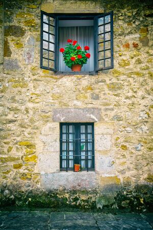 SANTILLANA DEL MAR,CANTABRIA,SPAIN - 31 AUGUST,2016: Old stone building with several windows decorated with plants in potsのeditorial素材