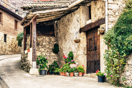 Stone old house at street with wooden doors and pots with plants near.のeditorial素材