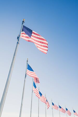 American flags on flagpoles on blue sky background.の写真素材