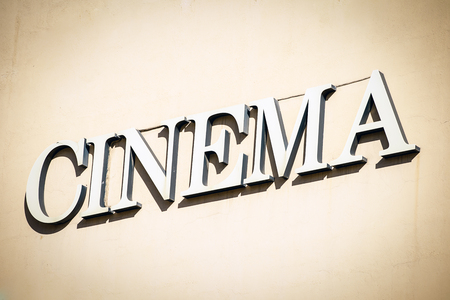 Front view of sign with letters pointing to cinema on wall.の写真素材