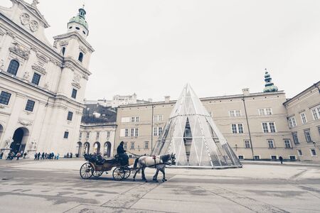 SALZBURG, AUSTRIA - MARCH 12: View on ancient Salzburg square with cathedral and carriage with horses on March 12, 2016 in Salzburg, Austria.のeditorial素材