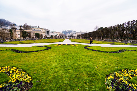 SALZBURG,GERMANY - 11 MARCH 2016: Tourists walking in spring bright park under cloudy sky on March 11, 2016 in Salzburg,Austria