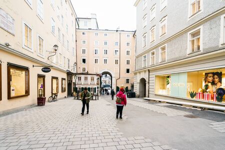 SALZBURG,AUSTRIA - 11 MARCH 2016: Back view of tourists walking along european street with different shops in Salzburg, Austriaのeditorial素材
