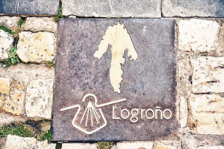 Way of St. James - 11.09.2016 Arrow with scallop shell symbol on bronze plate on pavement.のeditorial素材