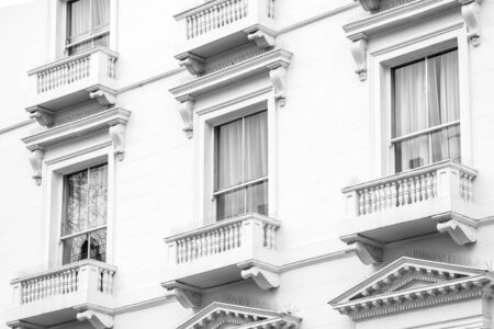 Horizontal outdoors black and white shot of the windows with the small balconies. 