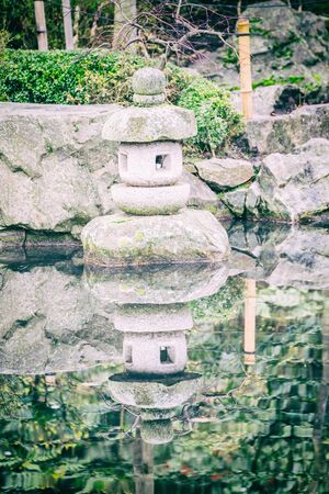 The small monument made with stones placed in a calm pond. Vertical outdoors shot.