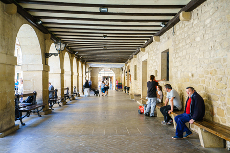 ALAVA,SPAIN - 6 AUGUST, 2016:people sitting on benches and walking along sidewalk with archsのeditorial素材