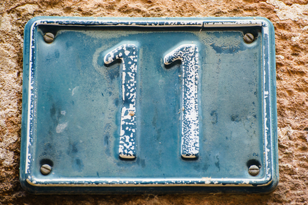 Close up shot of plate with number eleven on old wall of building .の写真素材