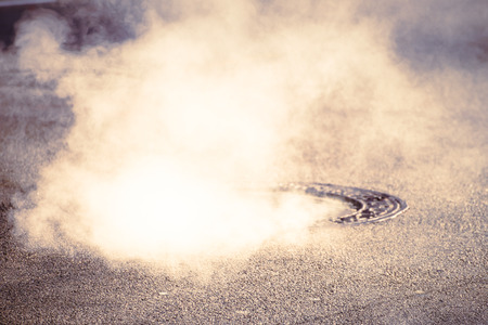 A manhole with steam in asphalt road in Boston, USA.の写真素材