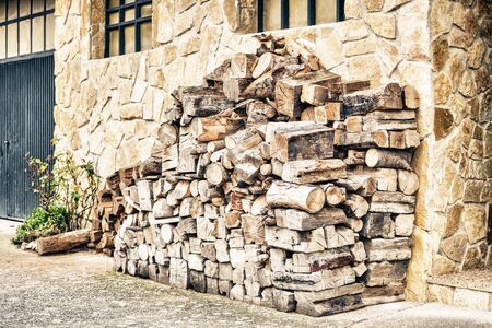 Big pile of wooden logs near stone wall.の写真素材
