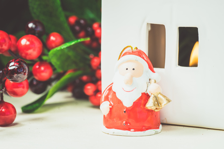 Close up of Christmas decorations and figurine of Santa Claus with bells standing on wooden surface. の写真素材
