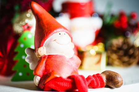 Close up of cute Christmas toy in red cap on blurred background of festive decorations. の写真素材